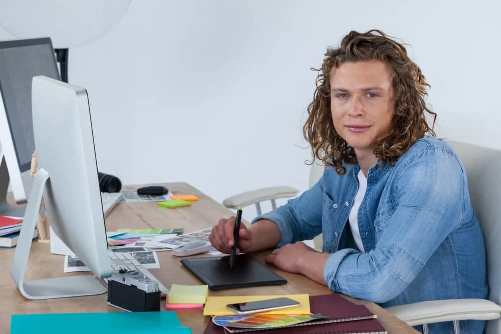 Grafička upravuje fotografii na monitoru v kanceláři.