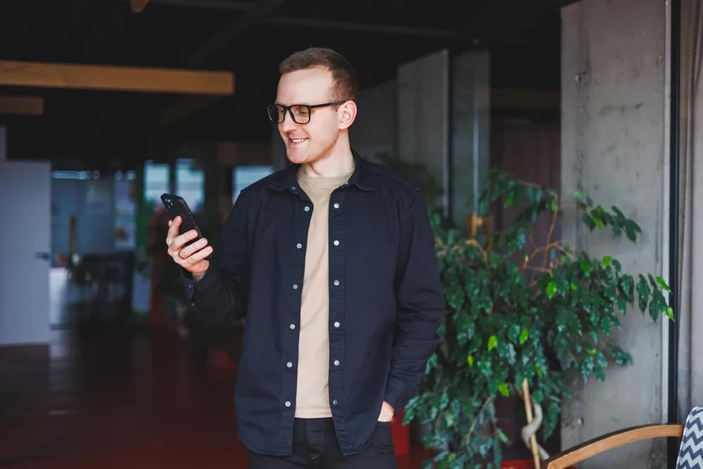 Pracovník v kanceláři používá mobilní telefon.