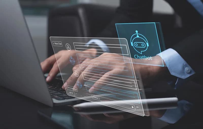 Člověk pracuje u počítače s digitálním asistentem na obrazovce.