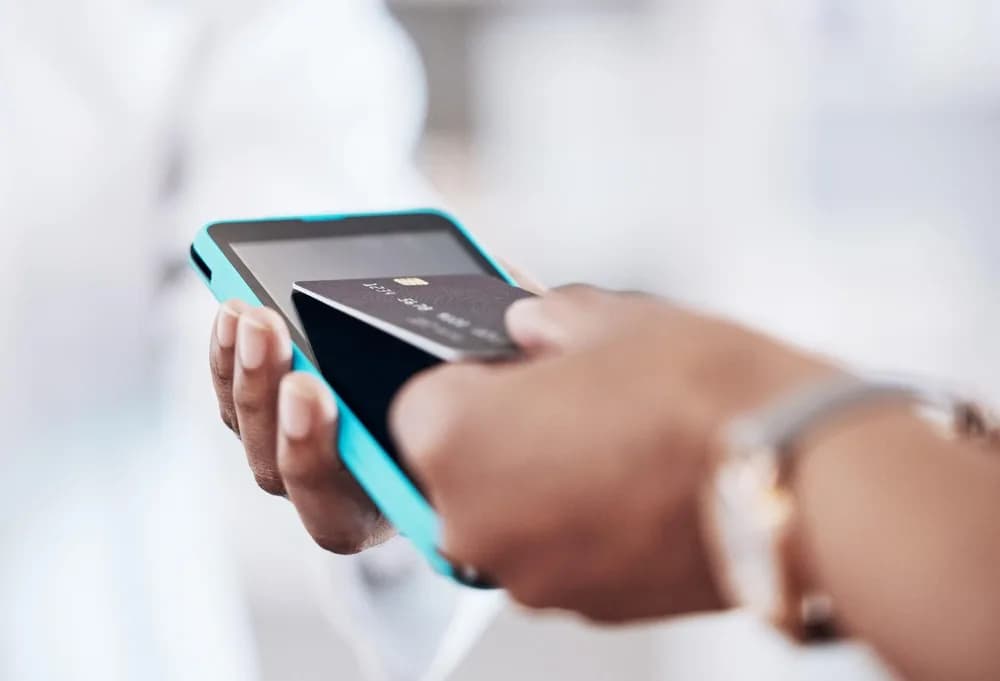Člověk přikládá telefon k platebnímu terminálu.