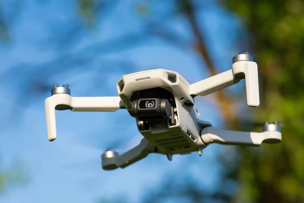 Autonomní dron letí nad otevřenou krajinou.