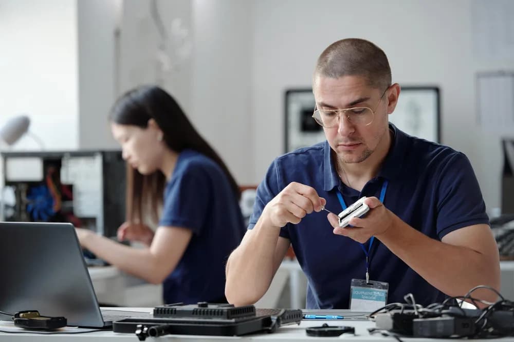 Technik v kanceláři zkoumá malé elektronické zařízení.