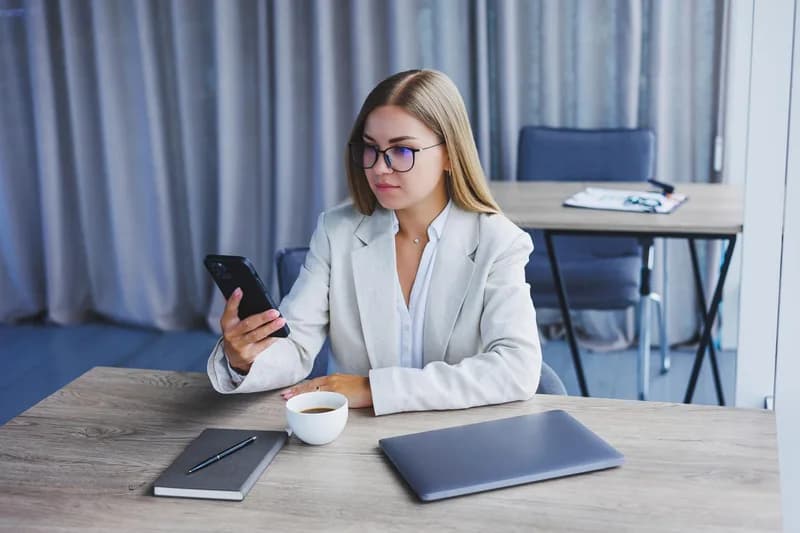 Zaměstnanec kontroluje zprávy na starším pracovním telefonu.