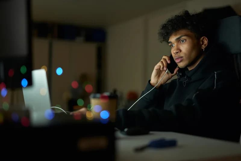 Neznámý volající telefonuje v potemnělé místnosti.