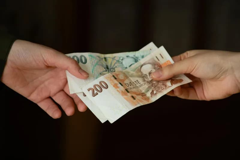 Předávání českých bankovek z ruky do ruky.