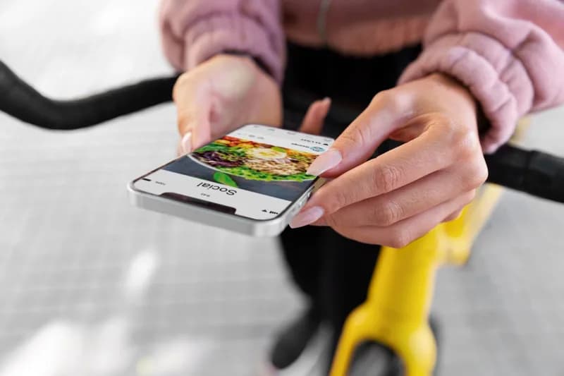 Kurýr na kole drží telefon s aplikací na rozvoz jídla.